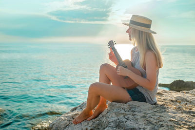 Summer vacation. caucasian women relaxing and playing on ukulele on beach, so happy luxury summer.