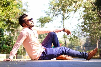 Side view of man sitting on road against sky