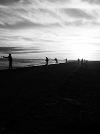 Silhouette people on beach against sky