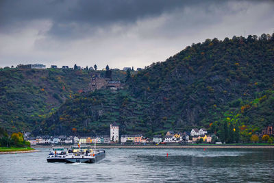Boat on rhine river by town against mountains