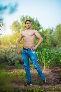 Full length portrait of shirtless man standing on land