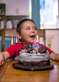 Young boy smiles as he sits before a lovely cake on his 5th birthday