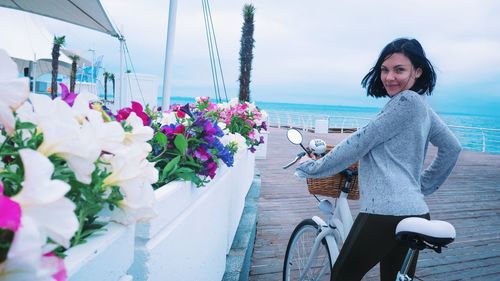 Portrait of woman with bicycle standing on promenade