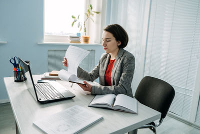 Young businesswoman, manager sitting at table in office and do notes in diary and calendar