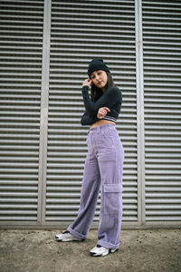 Fashionable young woman with cool attitude standing by metallic shutter