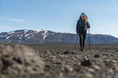 Person with umbrella on mountain against sky