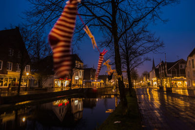 Illuminated buildings by river against sky at night