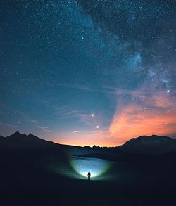 Silhouette person standing on field against sky at night