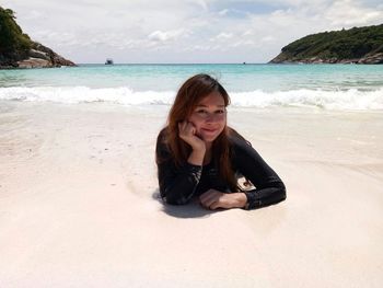 Portrait of beautiful mid adult woman lying at beach