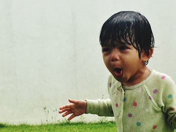 Close-up of playful girl sticking out tongue against wall