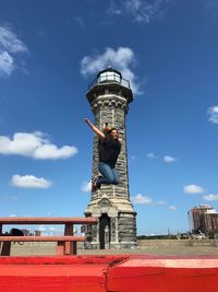 Full length of woman jumping against blackwell island light