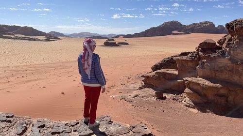 Rear view of man standing on sand at desert