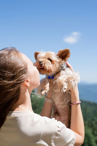 Caucasian woman smiling holding small dog yorkshire terrier. woman travel with pet, looking at view