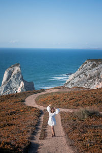 Woman standing on footpath against sea