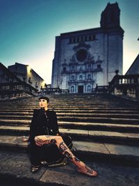 Portrait of woman sitting on staircase against building