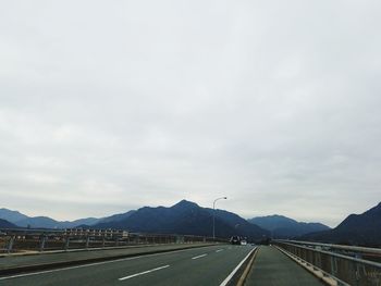 Road by mountains against sky