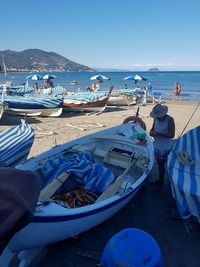 Boats moored on beach against clear blue sky