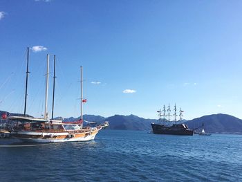 Boats in harbor against blue sky