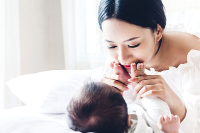 Close-up of smiling mother playing with son on bed at home