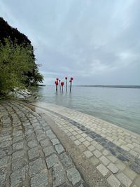 Rear view of people standing by sea against sky