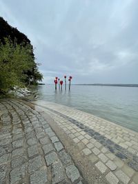 Rear view of people standing by sea against sky