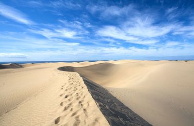 Scenic view of sand dunes against sky