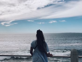 Rear view of woman looking at sea against sky