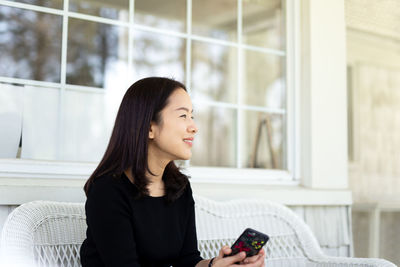 Young woman looking away while sitting on floor