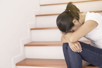 Rear view of woman sitting on staircase at home