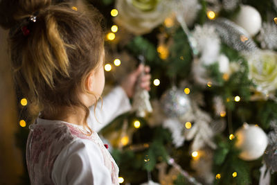 Rear view of girl with illuminated christmas tree