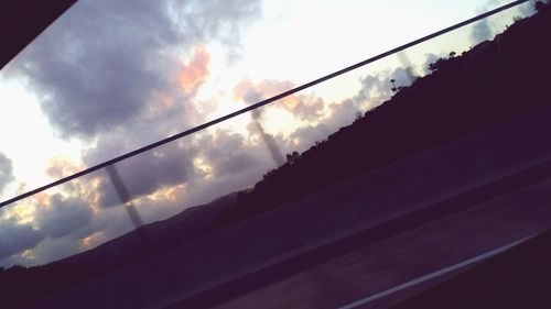 Low angle view of electricity pylon against cloudy sky