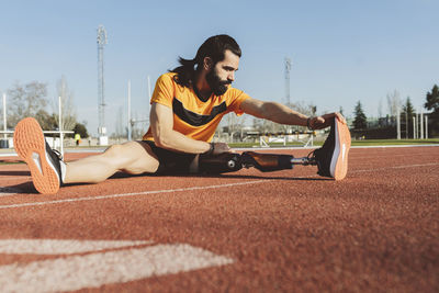 Athlete with prosthetic leg doing warm up exercise on running track