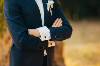 Midsection of man with arms crossed standing outdoors