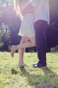Low section of couple standing on grass 