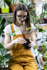 Florist work greenhouse. young woman freelancer gardener take care of plant in indoor garden or shop