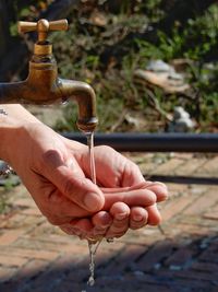 Close-up of hands below water faucet