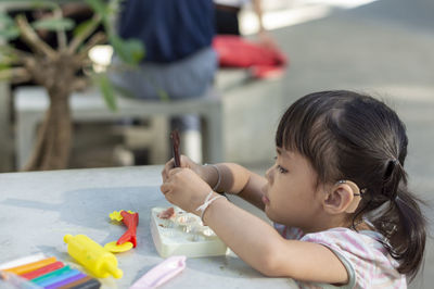 Close-up of cute girl playing with childs play clay at table outdoors