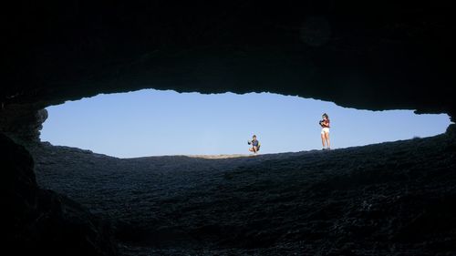 People standing on rock by mountain against sky