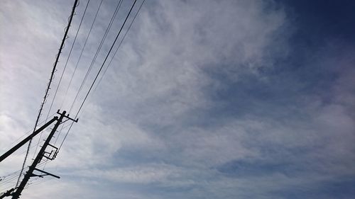 Low angle view of birds on cable against sky