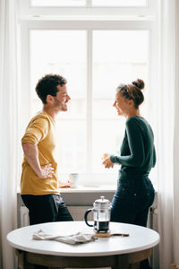 Woman standing by glass window on table