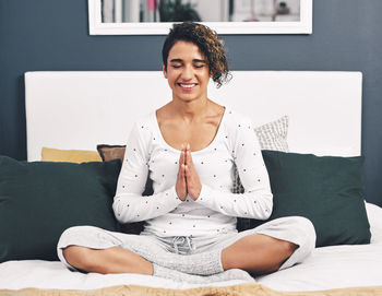 Portrait of young woman sitting on bed at home