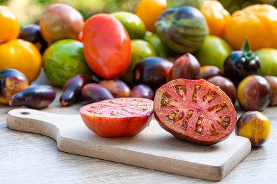 Table with a chopping board with sliced tomatoes and different colored tomatoes in the background