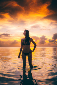 Full length of woman standing on beach against sky during sunset