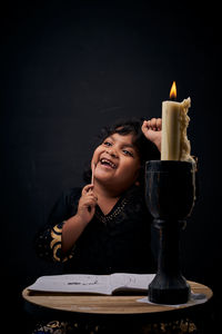 Portrait of boy holding drink against black background