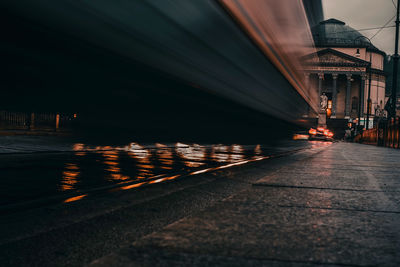 Illuminated road by buildings in city at night