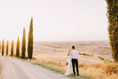 Rear view of couple walking on road against sky