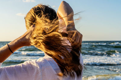 Rear view of woman with arms raised at beach