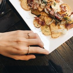 High angle view of woman hand by food on table