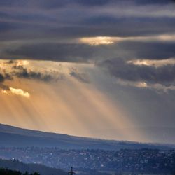 Scenic view of landscape against cloudy sky at sunset