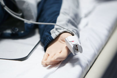 Cropped hand of patient on bed at hospital